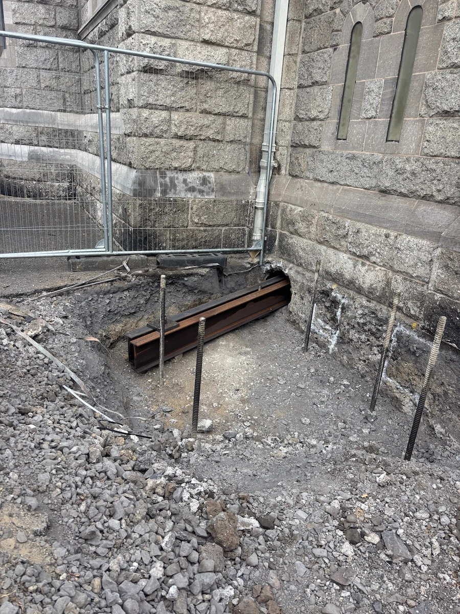Excavation and steel beam installation during underpinning works to an existing stone masonry building.